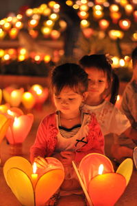 High angle view of people sitting on illuminated street at night