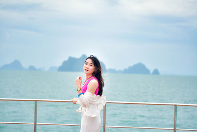 Portrait of young woman standing against sea