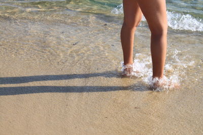 Low section of man standing on beach