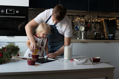 Father and his small daughter making christmas lollypops together.traditional family winter activity