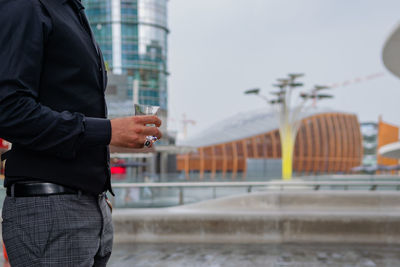Man holding umbrella standing on street in city