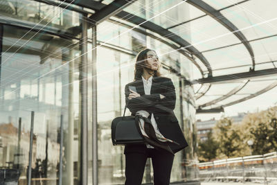 Young businesswoman standing in front of office