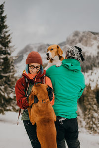 Close-up of dogs and a couple standing on snow