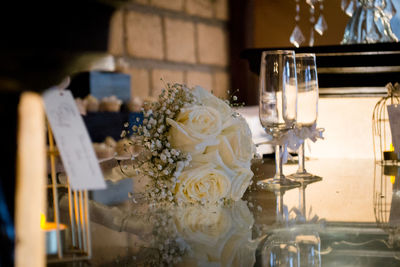 Empty wineglasses by rose bouquet on table at wedding reception