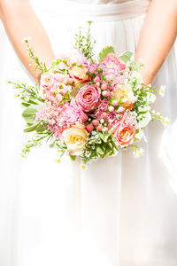 Midsection of bride holding flower bouquet