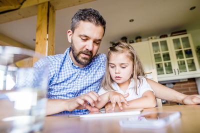 Father and daughter sitting at home using digital tablet