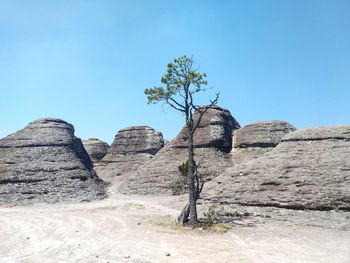 Low angle view of rocks against clear blue sky