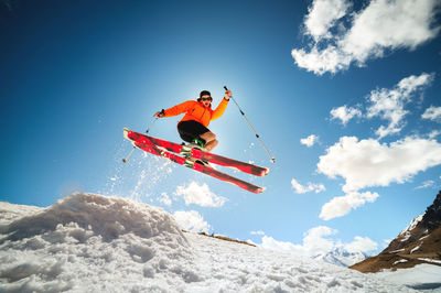 Young caucasian guy jumping from a springboard on skis