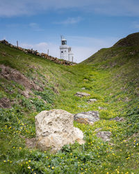 Lighthouse amidst rocks and buildings against sky