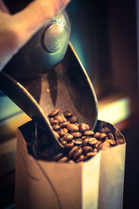 Cropped image of hand pouring roasted coffee beans in paper bag