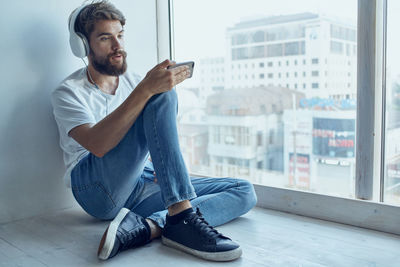 Portrait of young man sitting in window