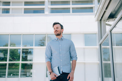 Young man standing against window of building