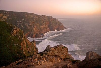 Rock formation on beach against sky during sunset