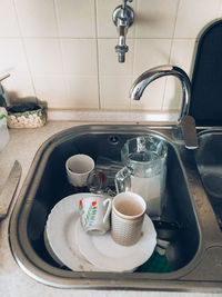 A sink full of dirty uncleaned dishes. trend cleanliness and order.