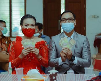 Portrait of bridegroom wearing mask holding banknotes during wedding ceremony