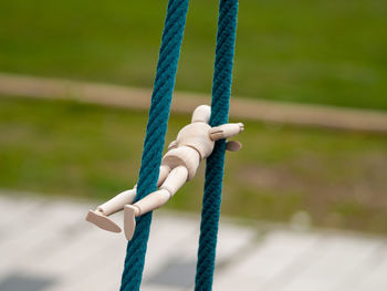 Close-up of wooden figurine hanging on ropes at playground