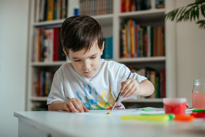Boy doing painting while sitting at home