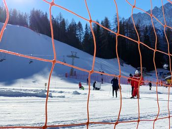 People skiing on snow covered land against sky