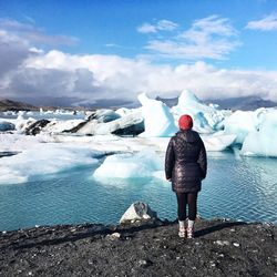 Rear view of woman standing in front of melting glaciers