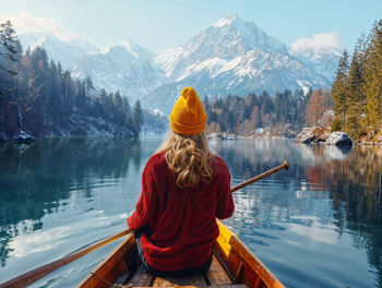 Rear view of woman sitting on lake