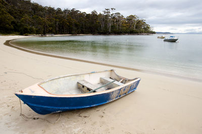 Boat moored on beach against sky