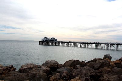 Pier on sea against cloudy sky