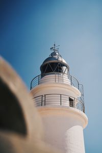 Low angle view of lighthouse by building against clear sky