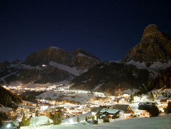 Houses by snowcapped mountains against sky at night