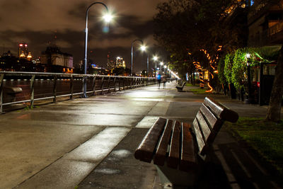 Illuminated street lights on footpath in city at night