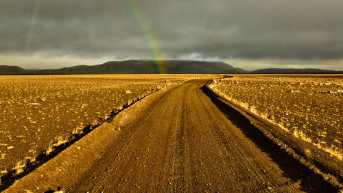 Road amidst field against sky