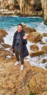 Portrait of a smiling young man standing on rock