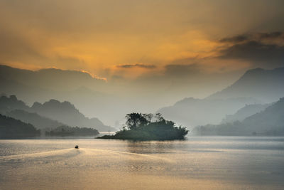 Scenic view of lake against mountains during sunset