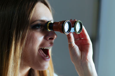 Close-up of woman with mouth open looking through binoculars
