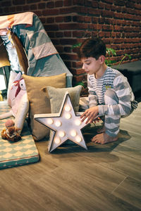 Male teen placing a star lamp helping preparing a slumber party
