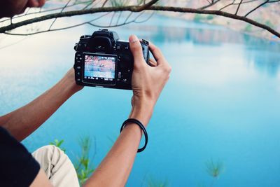 Cropped hand photographing river