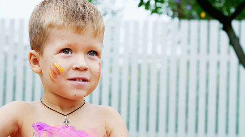 A little child, a four-year-old boy playing, painting with finger paints, decorating himself, in