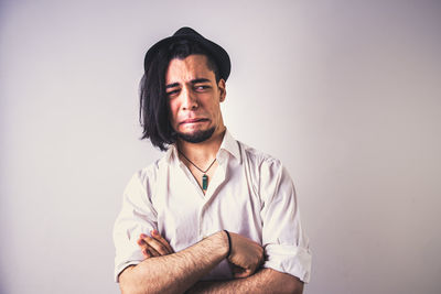 Portrait of young man sitting against wall