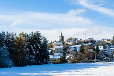 Snow covered trees and buildings against sky