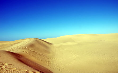 Scenic view of desert against clear blue sky
