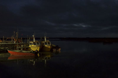 Boats moored at harbor against sky at sunset