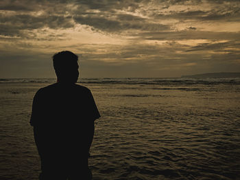 Rear view of silhouette man standing on beach