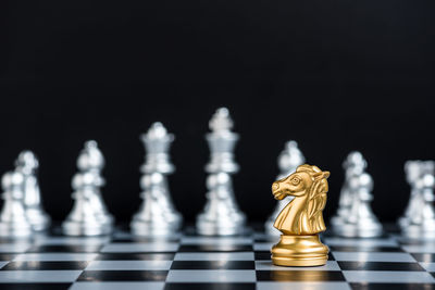 Close-up of chess pieces on board against black background