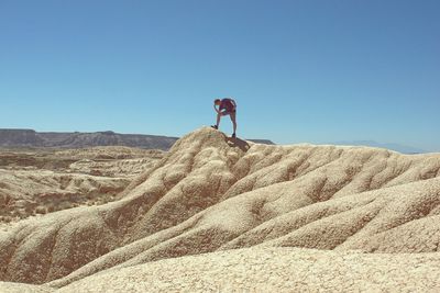 People on landscape against clear blue sky