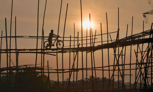 Silhouette man on construction site against sky during sunset