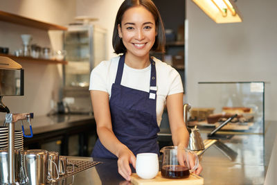 Portrait of young woman standing in cafe