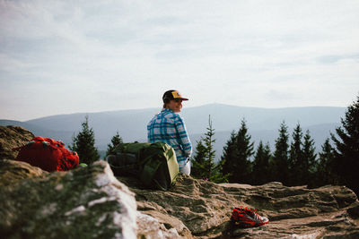 Rear view of woman sitting on rock against mountains