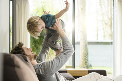 Happy father playing with son on sofa at home