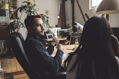 Entrepreneur talking to female colleague at workplace