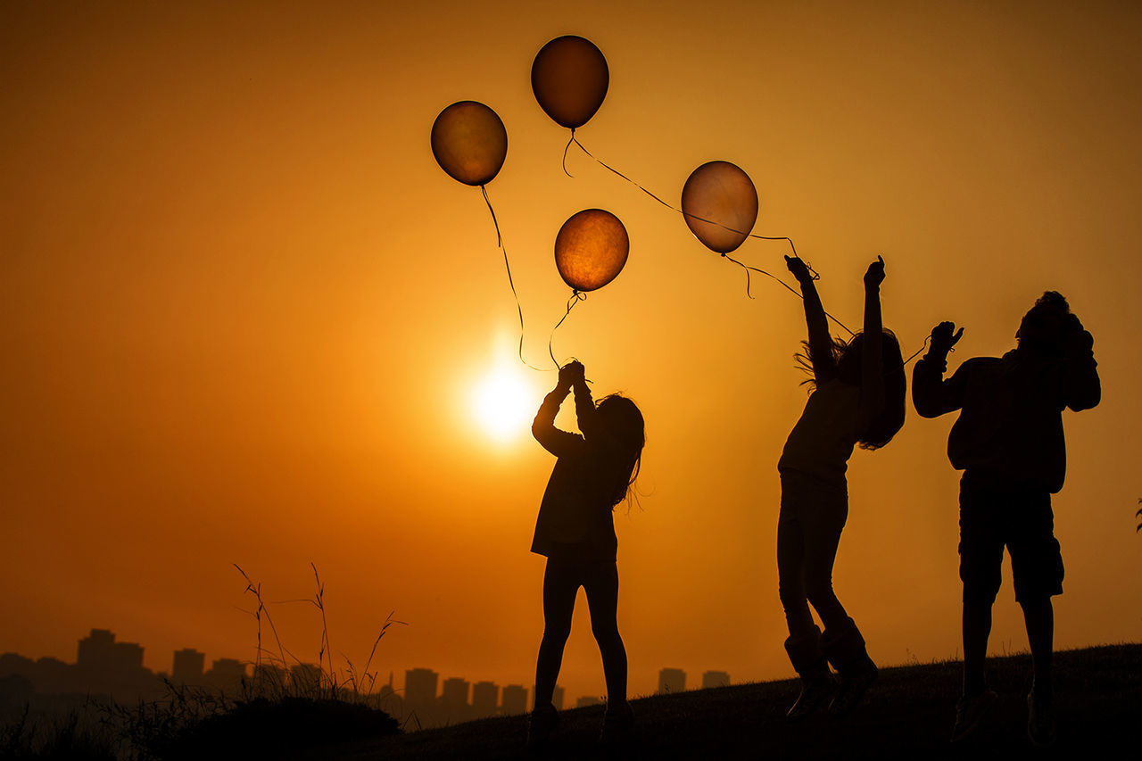 sunset, silhouette, lifestyles, leisure activity, sky, men, standing, orange color, full length, boys, togetherness, playing, childhood, enjoyment, fun, arms raised, sun, outdoors