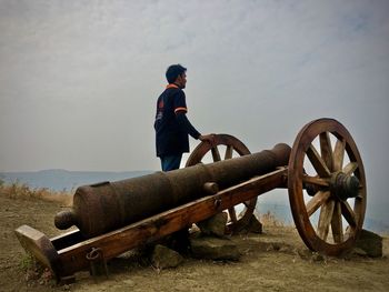 Side view of man standing on field against sky